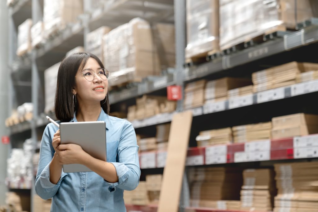 A woman takes inventory of the boxes in a warehouse to prepare for acquiring a vertical carousel storage system